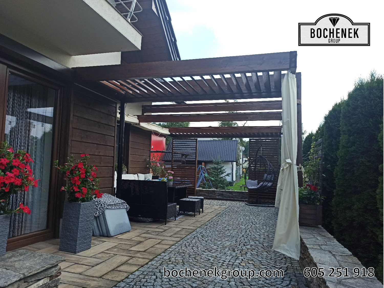 Pergola Kleopatra z drewnianym tarasem i meblami ogrodowymi pokazana w dzien oraz po zmroku